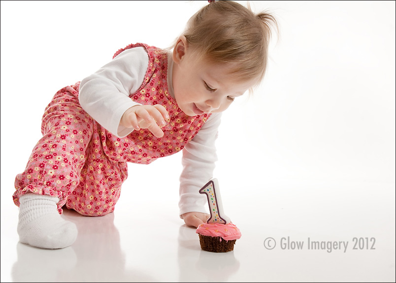 A baby celebrates her first-year with a cupcake in a Kansas City photographer's studio