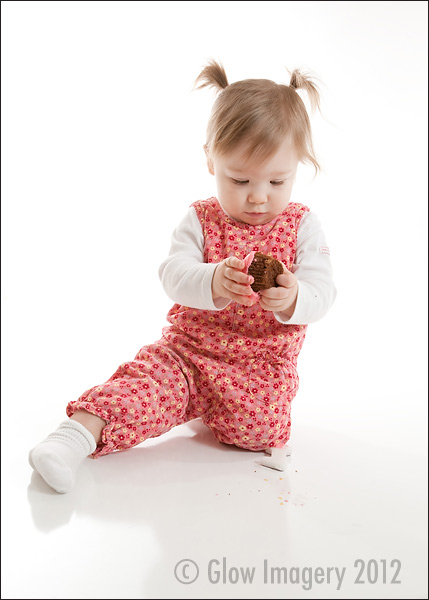 A baby celebrates her first-year with a cupcake in a Kansas City photographer's studio